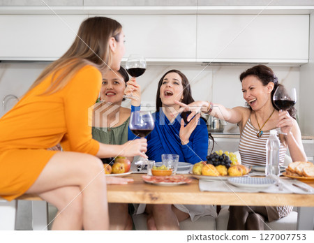 During gathering with friends, woman sit on table, enjoying food and wine, chatting, talking During gathering with friends, woman sit on table, enjoying food and wine, chatting, talking 127007753