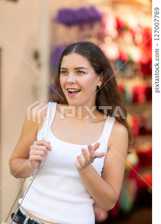 Young girl is looking for something at street market - looking at goods with interest Young girl is looking for something at street market - looking at goods with interest 127007769