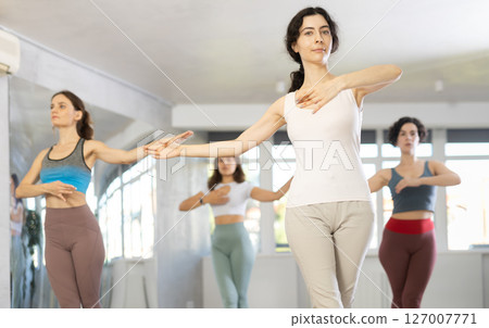 Group of active women learning modern dance movements at class together Group of active women learning modern dance movements at class together 127007771