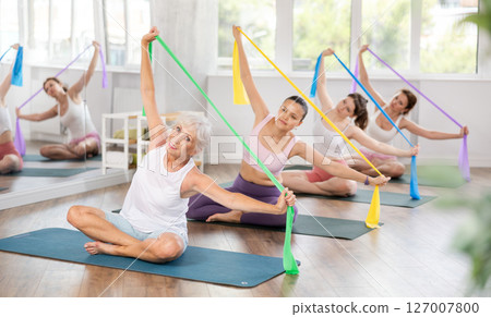Elderly woman exercises with pilates band Elderly woman exercises with pilates band 127007800
