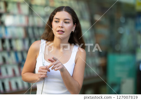 Smiling brunette looking at storefront during city walk Smiling brunette looking at storefront during city walk 127007819