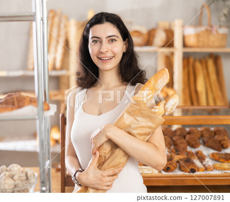 Young woman buying baguettes in bakery Young woman buying baguettes in bakery 127007891