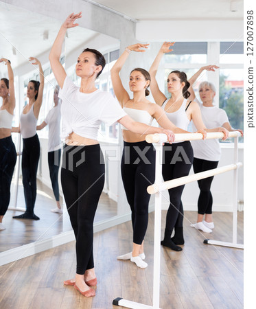 Girls in ballet class perform third position with participation of mature female mentor Girls in ballet class perform third position with participation of mature female mentor 127007898