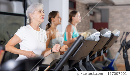 Elderly woman in sportswear are running on treadmill in crossfit gym Elderly woman in sportswear are running on treadmill in crossfit gym 127007901