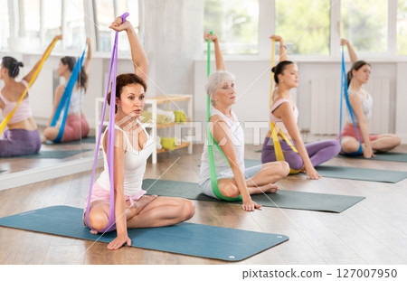 Woman exercising with resistance band in group fitness class Woman exercising with resistance band in group fitness class 127007950