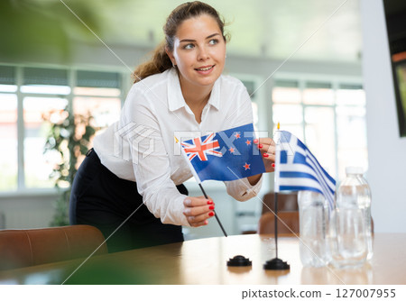 Young female secretary preparing room for international negotiations between greece and new zealand Young female secretary preparing room for international negotiations between greece and new zealand 127007955