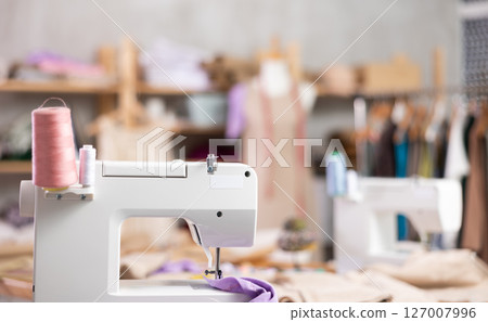 Sewing machine with thread spools in tailoring workshop 127007996