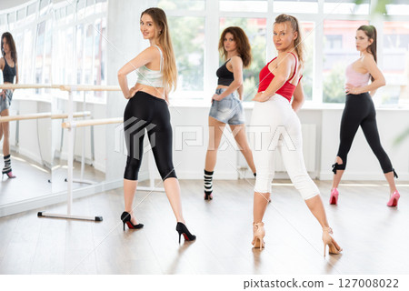 During lesson, girl learn to move and perform dance in heels with women companions, back view During lesson, girl learn to move and perform dance in heels with women companions, back view 127008022