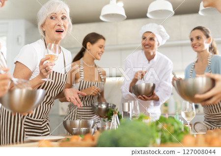 Elderly woman talks and drinks with group during master class 127008044
