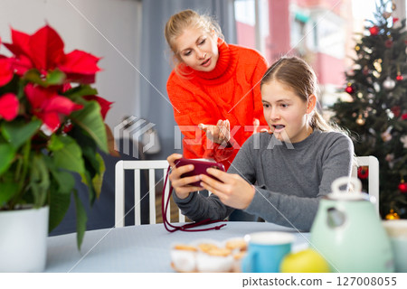 Mother tries to talk to daughter while daughter plays on smartphone Mother tries to talk to daughter while daughter plays on smartphone 127008055