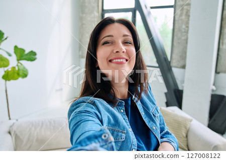 Selfie portrait happy beautiful woman in home interior 127008122