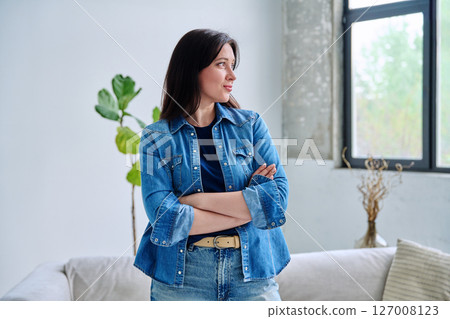 Portrait of beautiful young confident woman in home interior 127008123