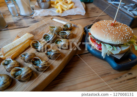 Gourmet escargot platter with classic cheeseburger on wooden table Gourmet escargot platter with classic cheeseburger on wooden table 127008131