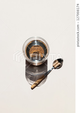 Illuminating Glass of Water and Spoon with Two Pills on Light Background, Promoting Healthy Lifestyle. 127008174