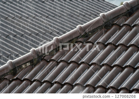 Heavy rainfall on carcked hip rafters and old roof tiles. 127008208