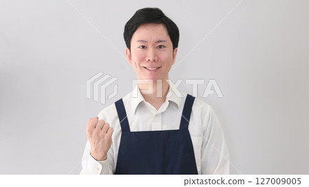 A smiling man in an apron doing a fist pump 127009005