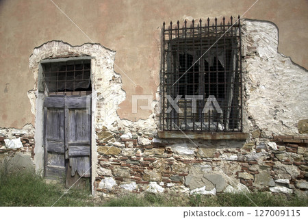 Old wooden door on a house wall. Conceptual image. Wooden Door on an Old House Wall. Architectural Details Worn and Weathered by Time.  127009115