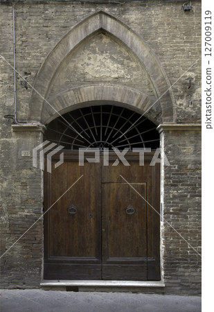 Old wooden door on a house wall. Conceptual image. Wooden Door on an Old House Wall. Architectural Details Worn and Weathered by Time.  127009119