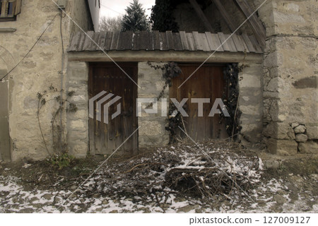 Old wooden door on a house wall. Conceptual image. Wooden Door on an Old House Wall. Architectural Details Worn and Weathered by Time.  127009127