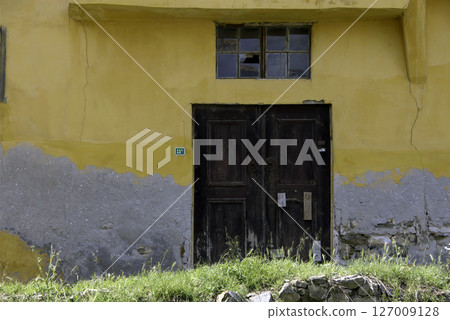 Old wooden door on a house wall. Conceptual image. Wooden Door on an Old House Wall. Architectural Details Worn and Weathered by Time. Old wooden door on a house wall. Conceptual image. Wooden Door on an Old House Wall. Architectural Details Worn and Weathered by Time. 127009128