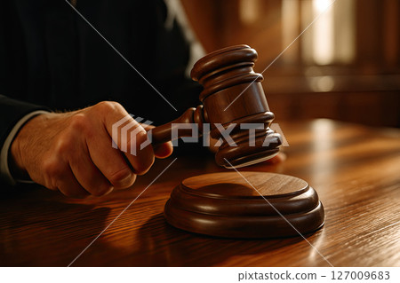 Judges Hand Holding Gavel Close-up in Courtroom Setting 127009683