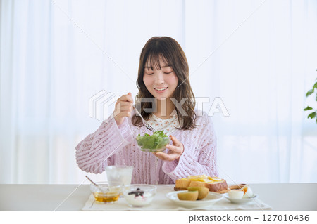 清爽的初夏早晨，一位女士正在吃早餐 127010436