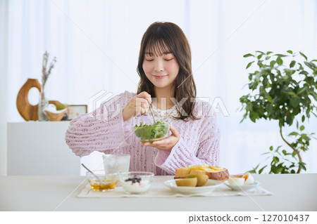 A woman eating breakfast on a refreshing early summer morning A woman eating breakfast on a refreshing early summer morning 127010437