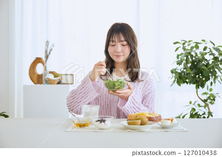 清爽的初夏早晨，一位女士正在吃早餐 127010438