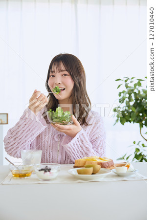 A woman eating breakfast on a refreshing early summer morning 127010440