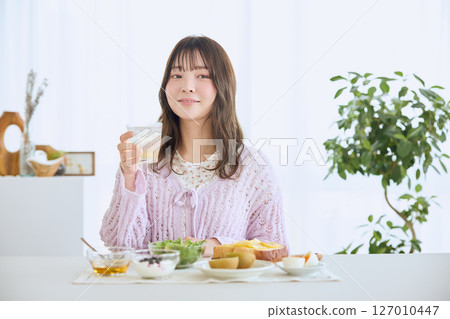 A woman eating breakfast on a refreshing early summer morning 127010447