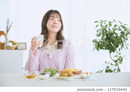 清爽的初夏早晨,一位女士正在吃早餐 清爽的初夏早晨,一位女士正在吃早餐 127010448