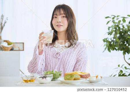 A woman eating breakfast on a refreshing early summer morning A woman eating breakfast on a refreshing early summer morning 127010452