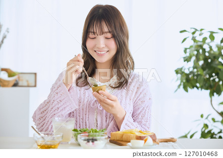 A woman eating breakfast on a refreshing early summer morning A woman eating breakfast on a refreshing early summer morning 127010468