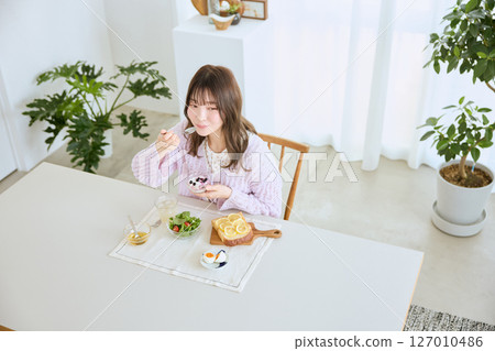 A woman eating breakfast on a refreshing early summer morning 127010486