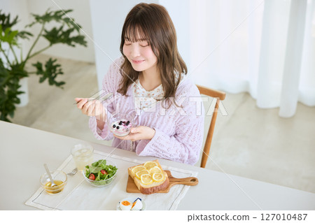 A woman eating breakfast on a refreshing early summer morning A woman eating breakfast on a refreshing early summer morning 127010487