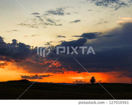 The sun setting on the horizon and a dramatic landscape The sun setting on the horizon and a dramatic landscape 127010561