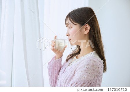 一位女士在窗邊喝著一杯果汁 一位女士在窗邊喝著一杯果汁 127010710