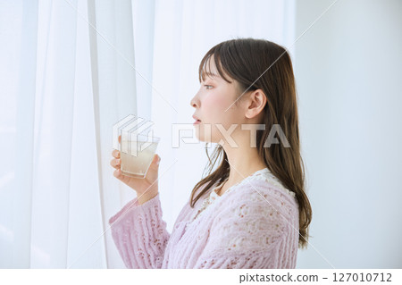 一位女士在窗邊喝著一杯果汁 127010712