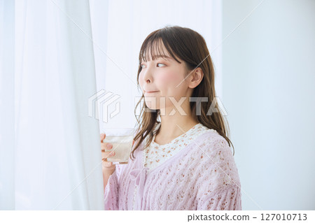一位女士在窗邊喝著一杯果汁 127010713