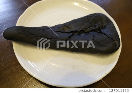 Place the black naan, which resembles Godzilla's tail, on the plate. Place the black naan, which resembles Godzilla's tail, on the plate. 127011553