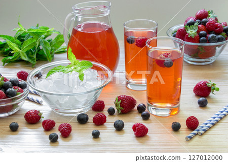 Enjoy a vibrant selection of berry infused drinks in tall glasses with ice, fresh mint, and mixed berries ideal for lively summer gatherings and celebrations. 127012000