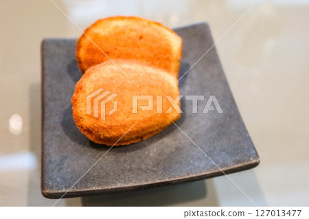 close up two pieces of shell-like Madeleine cakes on a serving plate with copy space 127013477