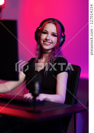 Young gamer streaming in a vibrant room with colorful lighting 127014154