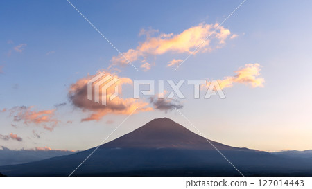 Mount Fuji stands in perfect symmetry beneath a vast sky, with sunset-lit clouds drifting above Mount Fuji stands in perfect symmetry beneath a vast sky, with sunset-lit clouds drifting above 127014443