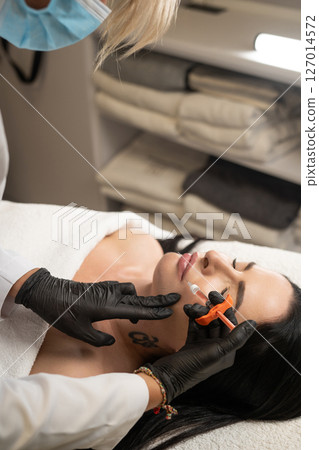 Syringe near woman's chin, beauty injections with fillers for chin shape correction. 127014572