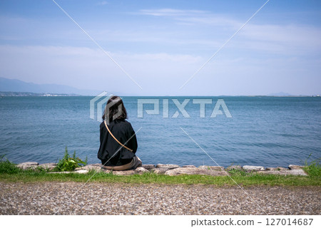 一位女士坐在琵琶湖岸邊，望著湖面的背影 127014687