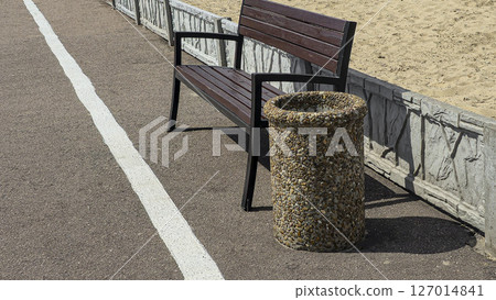Wooden benches and trash bins line the side of the road in a park recreation area 127014841
