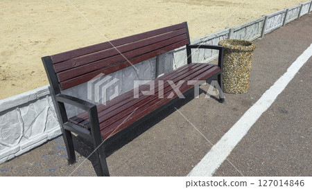 Wooden benches and trash bins line the side of the road in a park recreation area 127014846