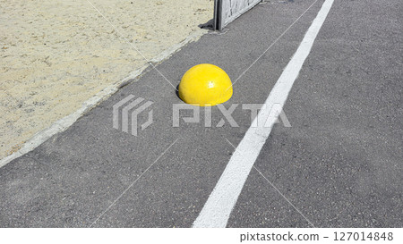 Hemispherical yellow concrete stop stone on asphalt. No entry. 127014848