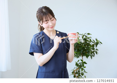 Dental hygienist giving brushing instructions 127014931
